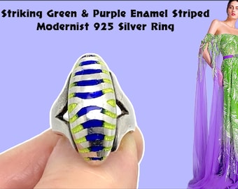 Puede incluir: Un anillo modernista de plata 925 con un llamativo diseño a rayas esmaltadas en verde y morado. El anillo tiene una forma única y presenta una combinación de colores plata, verde, azul y morado. El texto "Striking Green & Purple Enamel Striped Modernist 925 Silver Ring" es visible.