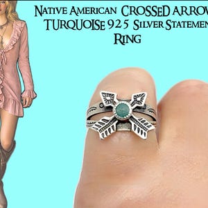 May include: A silver ring with a turquoise stone center, featuring a crossed arrow design. The ring is on a finger, with the text "NATIVE AMERICAN CROSSED ARROWS TURQUOISE 925 SILVER STATEMENT RING" in the background. The ring is a statement piece.