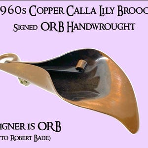 Puede incluir: Un broche de lirio calla de cobre, firmado "ORB HANDWROUGHT". El diseñador es Otto Robert Bade.