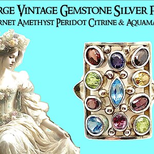 May include: Large vintage silver ring with a rectangular setting featuring a variety of colorful gemstones, including garnet, amethyst, peridot, citrine, and aquamarine.  The ring is set in a silver frame with a decorative design.
