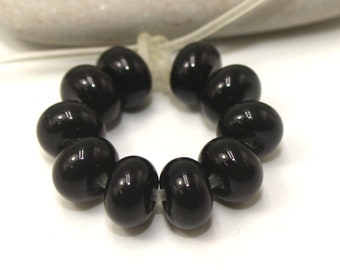 May include: A strand of black glass beads, strung on a clear cord, with a glossy finish.