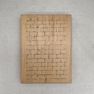 Könnte beinhalten: Rechteckige Holzplakette mit einem Mauerwerk-Design, das in die Oberfläche geätzt ist. Das Ziegelmuster wird mit dunklen Linien erstellt, und das Holz hat eine natürliche, hellbraune Farbe. Die Plakette wird vor einem neutralen Hintergrund präsentiert.