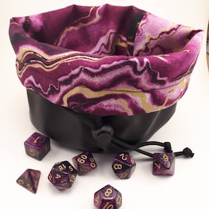 May include: Purple and gold dice with black and gold swirl pattern in a purple and gold marbled drawstring bag.
