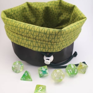 May include: A green fabric dice bag with a geometric pattern, filled with green and white dice. The dice are numbered 2, 4, 5, 6, 9, 11, and 13.