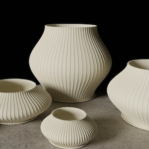 Könnte beinhalten: Fünf weiße Keramikvasen mit gerippter Textur. Die Vasen sind in einer Reihe vom größten zum kleinsten angeordnet.