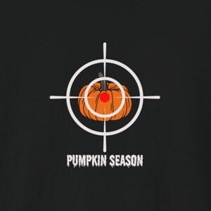 May include: A white target with a pumpkin in the center. The pumpkin is orange with a green stem and a red dot in the center. The text "Pumpkin Season" is below the target.
