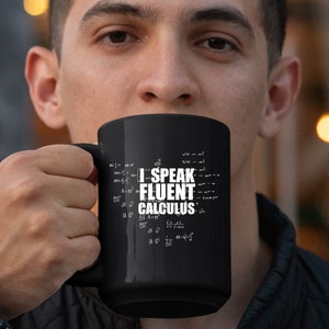 Puede incluir: Una taza de café negra con un diseño blanco que dice "Hablo cálculo con fluidez" rodeada de ecuaciones matemáticas.
