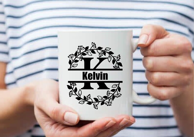 May include: White ceramic mug with a black floral wreath design and the letter "K" in the center. The name "Kelvin" is written below the letter.