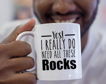 May include: White ceramic coffee mug with black text that reads "Yes! I really do need all these Rocks".