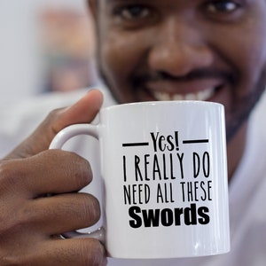 Peut inclure: Une tasse en céramique blanche avec une inscription noire qui dit "Oui ! J'ai vraiment besoin de toutes ces épées".