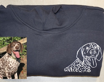 Op de afbeelding: Een donkerblauw hoodie met een witte omtrek van een hond met zijn tong naar buiten. De hond is een Duitse Korthaar.