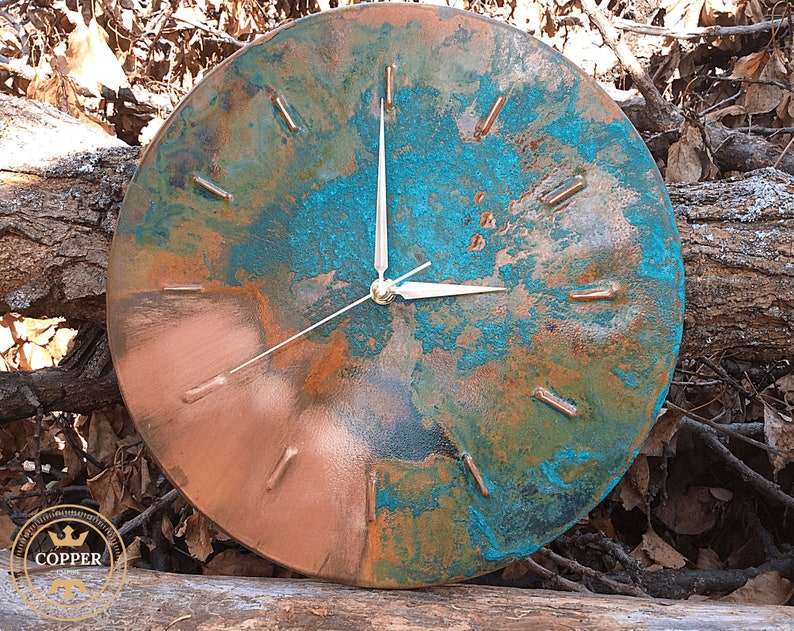 Rustic Handmade Old Copper Wall Clock with Silver Colored Hands on a natural wooden background under natural sunlight by Copper Empire