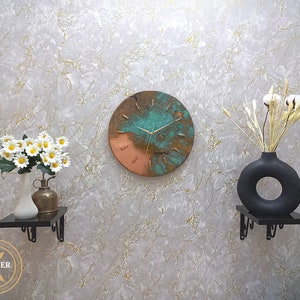 Rustic Handmade Old Blue Turquoise Patina Copper Wall Clock with Gold Colored Hands hanging on a white marble wall with black and brass decorative objects. by Copper Empire