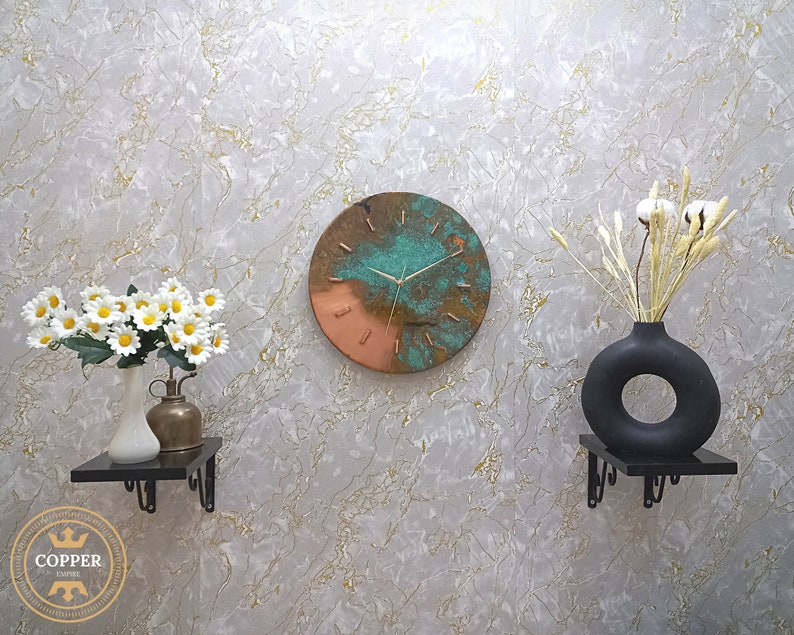 Rustic Handmade Old Blue Turquoise Patina Copper Wall Clock with Gold Colored Hands hanging on a white marble wall with black and brass decorative objects. by Copper Empire