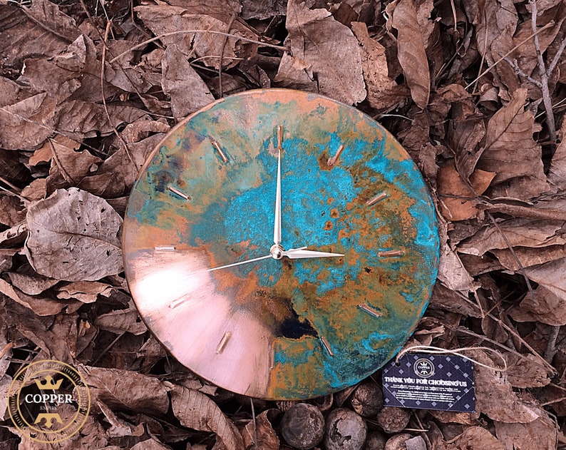 Art Deco Handmade Old Copper Wall Clock with Silver Colored Hands on a natural forest background under natural sunlight by Copper Empire