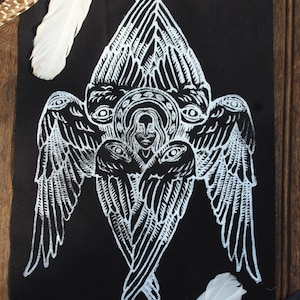 May include: A black and white illustration of an angel with multiple eyes and wings. The artwork features intricate linework and is set against a black background. White feathers are placed around the artwork.