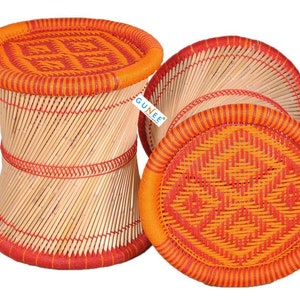 May include: Two woven bamboo stools with orange and red patterned tops. The stools are made of natural bamboo and have a traditional design.