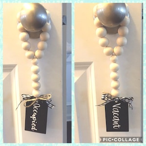 May include: Two white bead door hangers with black and white ribbon and a black tag. One tag says "Occupied" and the other says "Vacant".