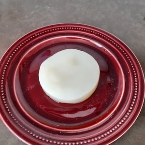 Pode incluir: Um bolo redondo branco em um prato vermelho com uma borda de contas.