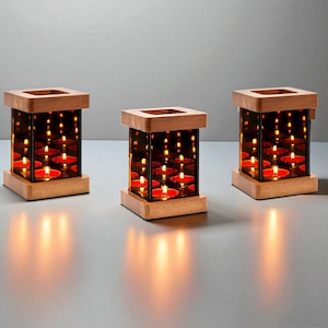 Peut inclure: Trois lanternes carrées avec des cadres et des bases en bois. Les lanternes ont des intérieurs en miroir qui reflètent les bougies rouges allumées à l'intérieur, créant un effet d'infini. Le dessus des lanternes est ouvert, et le design général est moderne et décoratif.