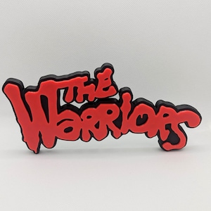 Può includere: Un cartello stampato in 3D rosso e nero con le parole "The Warriors" in un font stilizzato.