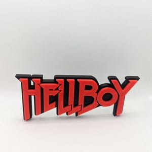 Puede incluir: Un logotipo impreso en 3D de la palabra "HELLBOY" en rojo y negro.