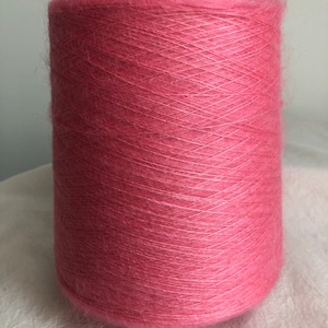Peut inclure: Une pelote de fil rose enroulée sur un tube en carton. Le fil est doux et moelleux, avec une texture délicate.