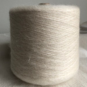 May include: A spool of beige yarn with a fuzzy texture.