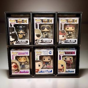 May include: A display case holding six Funko Pop! vinyl figures. The figures include Slash, Duff McKagan, Axl Rose, Janis Joplin, Forrest Gump, and Dee Snider. Each figure is in its original packaging.