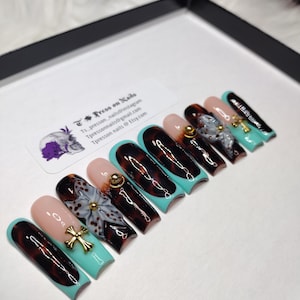 May include: Set of ten press-on nails with a tortoise shell and turquoise design. The nails feature a white flower with gold accents and a cross.