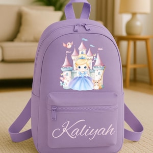 May include: A lilac backpack with a front pocket and adjustable straps. The backpack features a princess and castle graphic. The name "Kaliyah" is printed in cursive on the front pocket. The backpack has a top handle for carrying.
