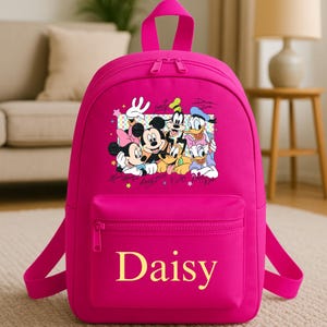 May include: A vibrant pink backpack with a Disney character graphic, including Mickey and Minnie Mouse, Goofy, Donald Duck, and Daisy Duck. The name "Daisy" is printed in yellow on the front pocket. The backpack has a top handle, adjustable straps, and a zipped front pocket.