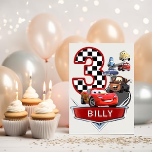 May include: A birthday card with a checkered number 3, red border, and Cars characters illustrations. The card has the name "BILLY" on a red banner. Cupcakes with candles and balloons in the background complete the scene.