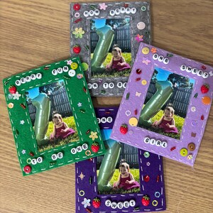 May include: Four handmade felt picture frames in green, gray, purple, and violet. Each frame has a photo of a baby with a number one balloon. The frames are decorated with beads, buttons, and the words "Berry Fun To Be One" and "One Sweet Girl".
