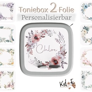 Könnte beinhalten: Ein quadratisches Toniebox-Gerät mit einem personalisierbaren Aufkleber, der ein Blumenkranz-Design und den Namen Chloe in der Mitte zeigt. Das Bild zeigt acht weitere quadratische Aufkleber-Optionen mit verschiedenen Blumenmustern und dem Text Toniebox 2 Folie Personalisierbar.