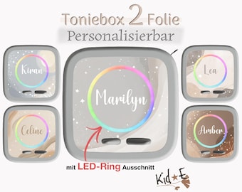 Puede incluir: Un conjunto de pegatinas cuadradas para reproductor de audio Toniebox, con nombres personalizables como Marilyn, Kiran, Lea, Celine y Amber. Los diseños incluyen remolinos abstractos, estrellas y un recorte circular para anillo LED. Texto: Toniebox 2 Folie Personalisierbar y mit LED-Ring Ausschnitt.