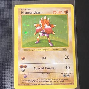 May include: A Hitmonchan Pokémon trading card. The card features a cartoon image of Hitmonchan, a humanoid figure with boxing gloves. The card text includes "Jab" and "Special Punch". The card is 4' 7" long and weighs 111 lbs.
