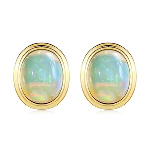 Pode incluir: Um par de brincos de tarracha ovais com opalas cabochão lisas e iridescentes, engastadas em aros de ouro amarelo polido. As opalas exibem um jogo de cores com reflexos verdes, azuis e laranja sobre uma base branca leitosa e translúcida.