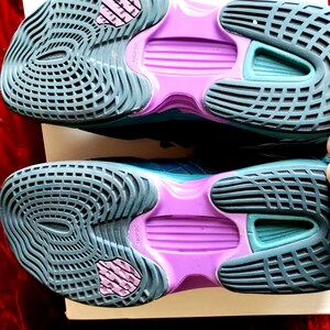 K&ouml;nnte beinhalten: Ein Paar t&uuml;rkisfarbene und violette Sportschuhe mit einer strukturierten Sohle. Die Schuhe haben eine violette Zwischensohle und eine t&uuml;rkisfarbene Au&szlig;ensohle.