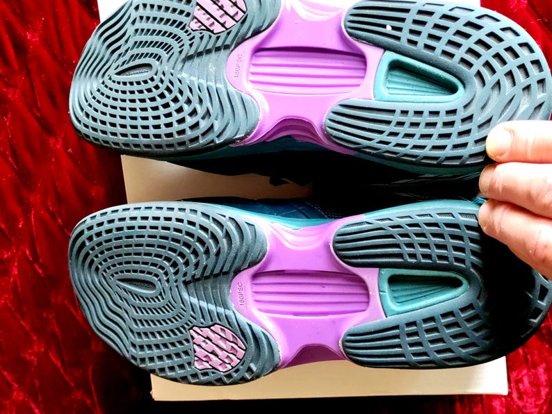 K&ouml;nnte beinhalten: Ein Paar t&uuml;rkisfarbene und violette Sportschuhe mit einer strukturierten Sohle. Die Schuhe haben eine violette Zwischensohle und eine t&uuml;rkisfarbene Au&szlig;ensohle.