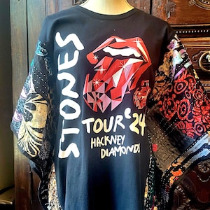 May include: A black t-shirt featuring a red lips and tongue graphic with a diamond-like faceted texture. The text reads STONES TOUR 24 HACKNEY DIAMONDS. The sleeves are constructed from multicolored, patterned fabric panels with various floral and geometric designs.