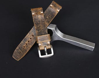 May include: A brown leather watch strap with distressed detailing and white stitching. The strap is folded in half and has a silver buckle.
