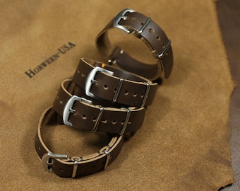 Puede incluir: Tres correas de reloj de cuero marrón con hebillas plateadas. Las correas están apiladas una encima de la otra y el logotipo de Horween-USA es visible en el fondo.