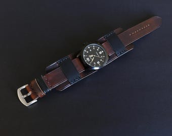 May include: A brown leather watch strap with a black leather insert. The watch face is black with white numbers and hands.