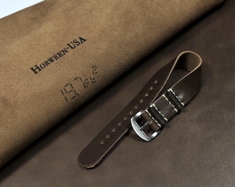 Puede incluir: Una correa de reloj de cuero marrón con costuras blancas y una hebilla plateada. La correa está hecha de cuero Horween, un cuero de alta calidad conocido por su durabilidad y longevidad. La correa se muestra sobre un trozo de cuero marrón con el logotipo de Horween-USA y la fecha 1971 estampada en él.