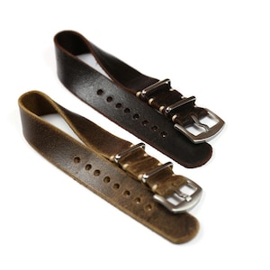 Puede incluir: Dos correas de reloj de cuero, una marrón y otra marrón oscuro, con costuras y hebillas metálicas.