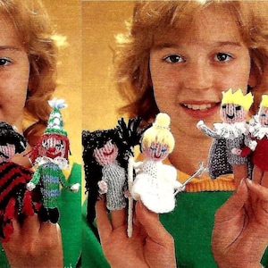 May include: A child is wearing a green shirt and holding up a set of finger puppets. The puppets are made of yarn and include a lion, a chef, a bandit, a clown, a witch, a bride, a king, and a queen.