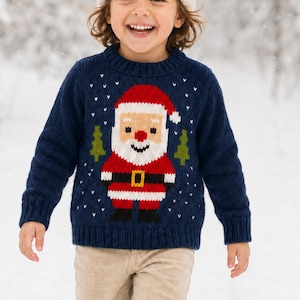 Könnte beinhalten: Ein dunkelblauer, langärmeliger Strickpullover mit einem zentralen Weihnachtsmann-Motiv, das eine rote Mütze, einen weißen Bart und einen schwarzen Gürtel zeigt, flankiert von zwei kleinen grünen Tannen und weißen Schneeflocken.
