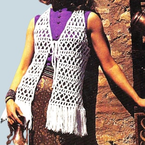 May include: A woman wearing a white crochet vest with fringe, over a purple top and patterned skirt. She is also wearing a purple headscarf and holding a small bronze jug. The background features a brick wall and bronze vessels.