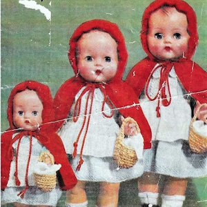 May include: Three knitted dolls dressed in red hooded cloaks and white dresses, each holding a small basket. The dolls have painted faces and are wearing white socks and black shoes.